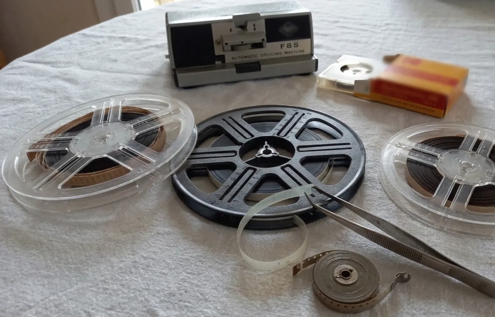 Bobines de film Super 8, colleuse et pince sur une nappe en lin